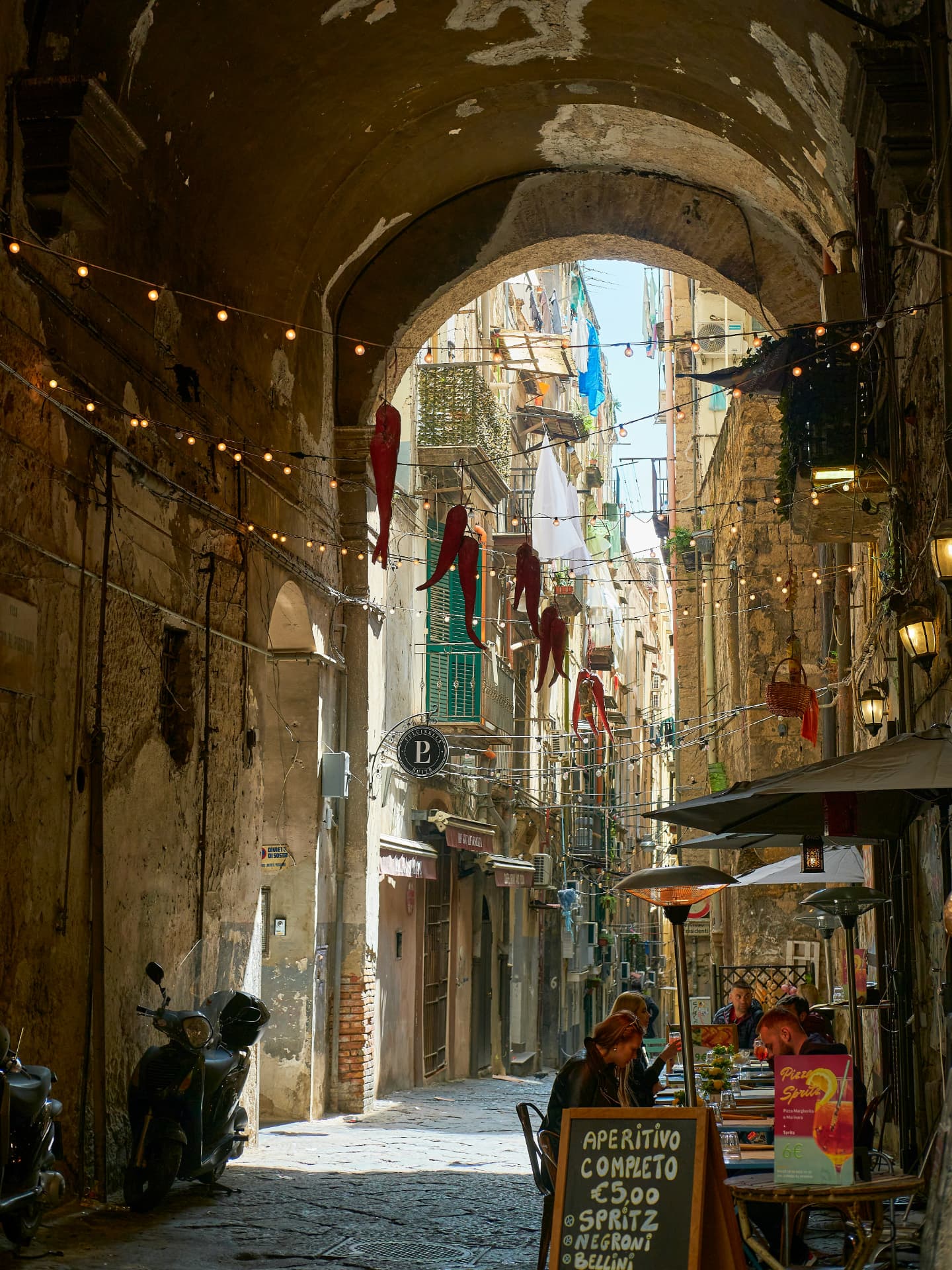 Sunlit alley with string lights in old Naples